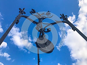 Old vintage antique medieval beautiful black iron forged wheel, a device for lifting goods against the blue sky