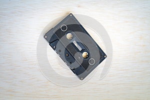 Old vintage audio cassette in black colour is on the wooden background
