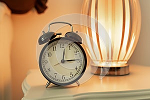 Old vintage black alarm clock located close-up on a white bedside table