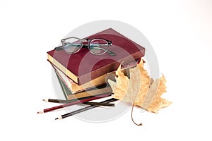 Old vintage book, glasses, autumn leave and color pencils isolated on white background