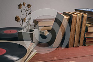 Old vintage books, vinyl records and a dry flower in a concrete vase