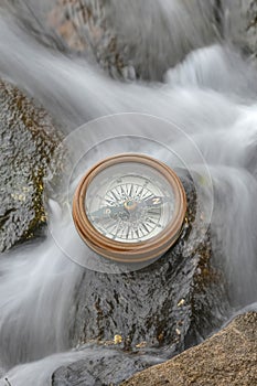 Old vintage brass navigation in a stream of water and on a rock