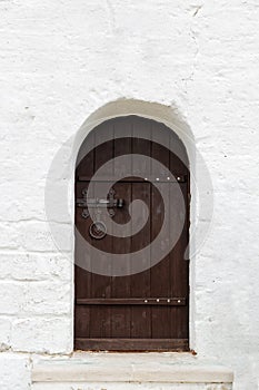 Old vintage brown wooden door in old white stone wall.