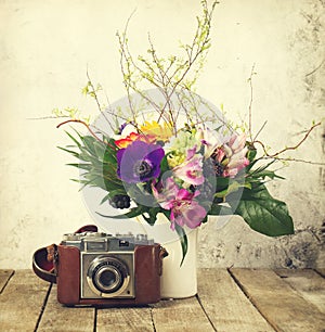 Old Vintage Camera with Beautiful Bouquet of Flowers on Wooden B