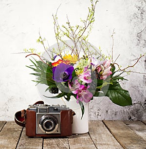 Old Vintage Camera with Beautiful Bouquet of Flowers on Wooden B