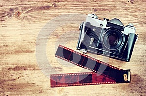Old vintage camera and film strips over wooden brown background