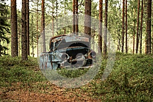 Old vintage car wreck standing in a forest in Sweden photo