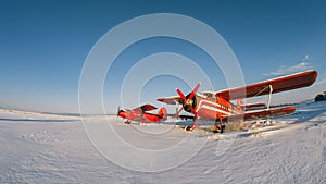 Old vintage classic airplane on snow covered airfield. Abandoned biplane in summer winter day with clear sky after snowfall