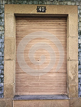 Old and vintage closed window with wooden shutter in a granite stone wall and blue tiles, with number 40 on top