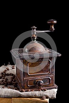 Old vintage coffee grinder with roasted coffee beans. Dark still life