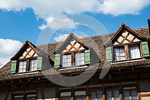 Old vintage European decorated attic windows with open wooden shutter and facade decoration in a small village in Switzerland.