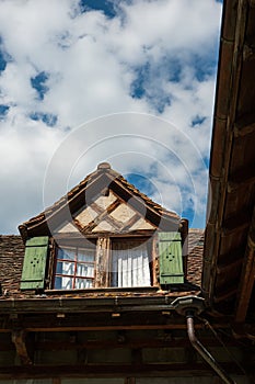 Old vintage European decorated attic windows with open wooden shutter and facade decoration in a small village in Switzerland.