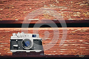 Old vintage film photo camera lying on wooden background. Copy space. Top view