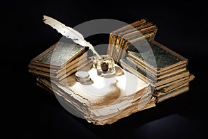 Old vintage fountain pen, books and inkwell on a black background