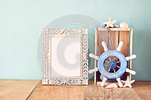 Old vintage frame with naurical wheel on wooden table. vintage filtered image