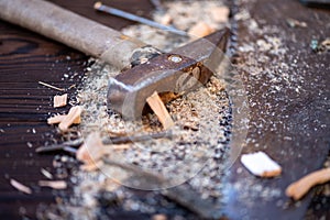 Old vintage hammer, wood saw, nails and sawdust on a wooden background, close-up, selective focus