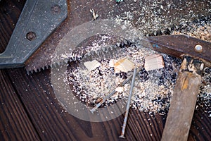 Old vintage hammer, wood saw, nails and sawdust on a wooden background, close-up, selective focus