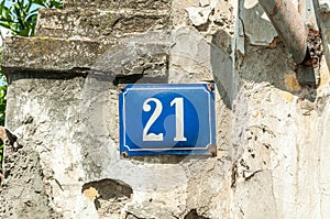 Old vintage house address metal plate number 21 twenty-one on the plaster facade of abandoned home exterior wall on the street s