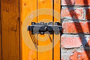 Old vintage iron lock on wooden yellow door on red brick wall background
