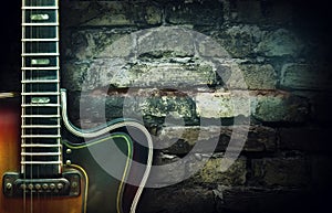 Old vintage jazz guitar on a brick wall background. Copy space. Background for concerts, festivals, music schools. Art