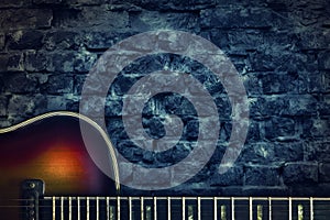 Old vintage jazz guitar on a brick wall background. Copy space. Background for concerts, festivals, music schools. Art