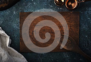 Old vintage kitchen utensils. Wooden Spoon, bowls, cutting board, napkin. Over dark slate board. Top view