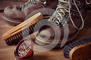 Old vintage leather boots with shoe brush on wooden background