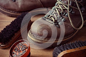 Old vintage leather boots with shoe brush on wooden background