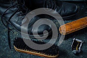 Old vintage leather boots with shoe brushes on dark background