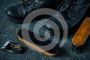 Old vintage leather boots with shoe brushes on dark background