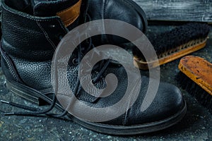 Old vintage leather boots with shoe brushes on dark background