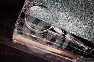 Old vintage magnifying glass with books on table