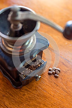 Old vintage manual grinder with roasted coffee beans in the coffee shop