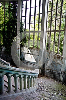 Old vintage marble spiral staircase at abandoned overgrown mansion