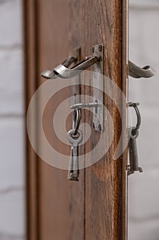 Old vintage metal keys inserted into the cabinet door. Vintage antiques concept