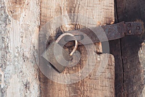 The old and vintage metal padlock with rust on the wooden door, locked for security