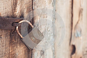 The old and vintage metal padlock with rust on the wooden door, locked for security