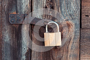 The old and vintage metal padlock with rust on the wooden door, locked for security