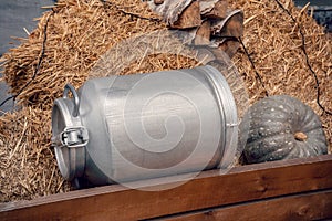 Old vintage milk churns. Aluminium Can for milk or water. Wooden Cart and logs as background