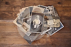 Old vintage monochrome photographs in sepia color are scattered on a wooden table, the concept of genealogy, the memory of