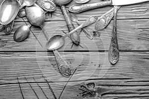 Old vintage ornamented cutlery on a wooden table. black and white photo