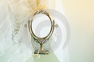 Old vintage oval mirror and beautiful white wedding dress and veil on chair. Copy space for mock up, montage or design layout