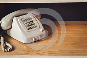 Old vintage phone with wire on wooden shelf, retro design close-up nostalgia