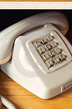 Old vintage phone with wire on wooden shelf, retro design close-up nostalgia