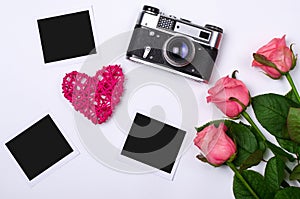 Old vintage photo camera and pink roses on a white background.