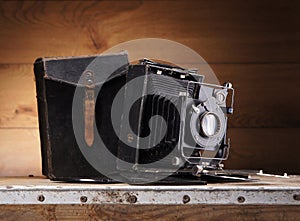 An old vintage photo camera on a wooden background