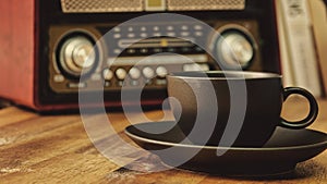 An old vintage radio and a cup of espresso on a wooden table