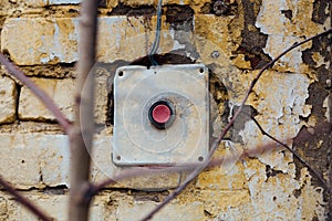 Old, vintage red button on the brick wall
