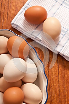 Old vintage retro bowl with raw farm eggs and two eggs lying on dishcloth in rustic style