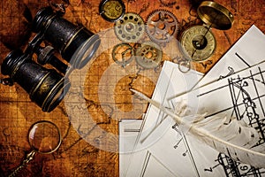 Old vintage retro compass and binoculars on ancient world map